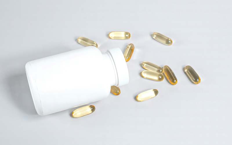 Top-down photo of copper supplement capsules beside a relaxed golden retriever and Persian cat on a natural wood surface
